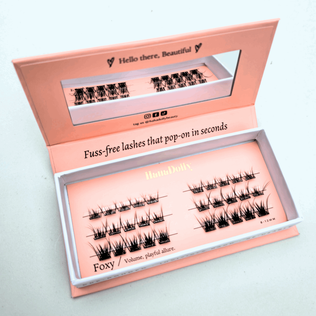 Angled flatlay of HanaDolly FOXY press-on lashes in an open pink box, showing individual lash clusters for easy application.
