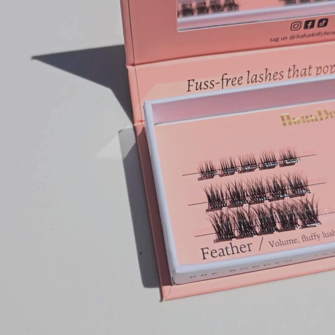 Close up video of HanaDolly's Feather press-on lashes in their pink box packaging with the top opened and zoomed in on the rows of pre-glued lashes inside.
