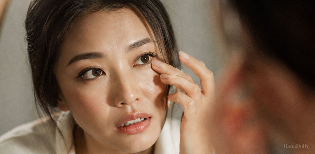 Asian woman gently rubbing her eye near her false lashes, showing lash irritation or discomfort in Singapore’s humid weather.
