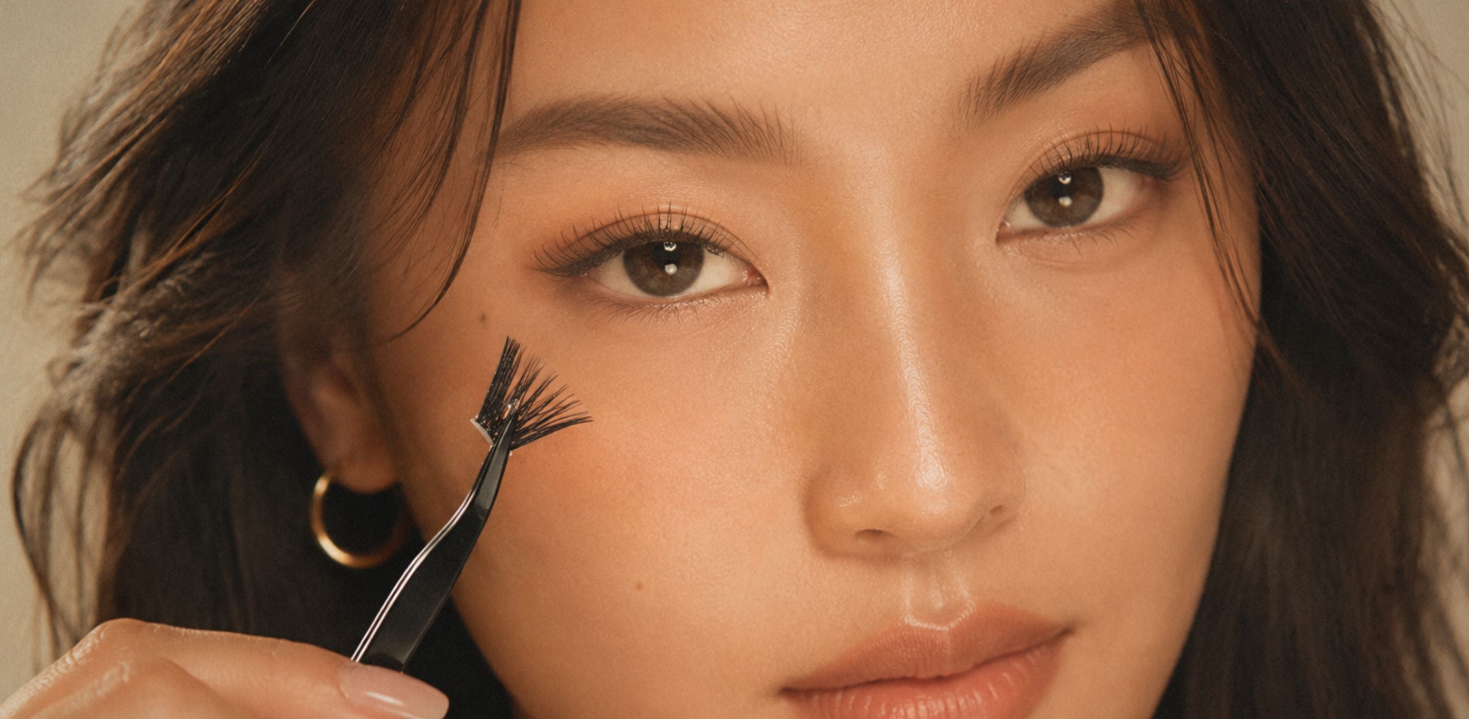 Close-up of an Asian woman using a lash applicator to apply false lashes, for a guide on where to buy false lashes in Singapore