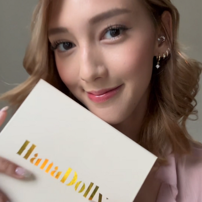 A beautiful female model holding HanaDolly DIY lash kit and smiling in a hanadolly customer testmonial