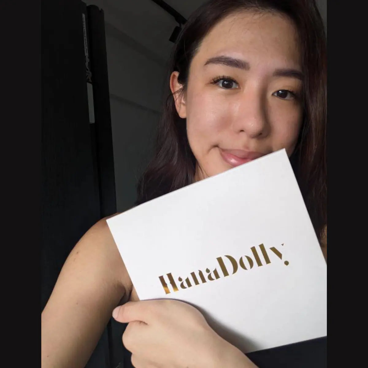 Woman showing HanaDolly press-on lash kit in customer testimonial photo