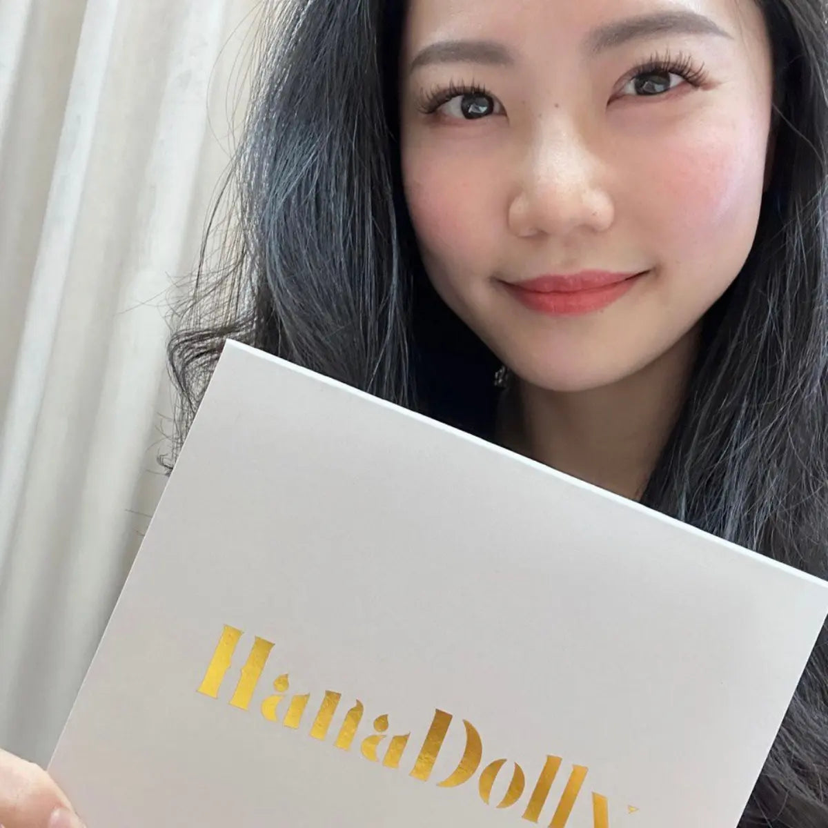 Female customer posing with HanaDolly lash kit and natural lash look