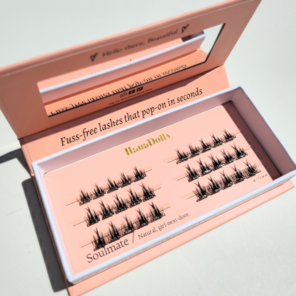 Angled flatlay of Soulmate press-on lashes in an open pink box, showing individual lash clusters for easy application.
