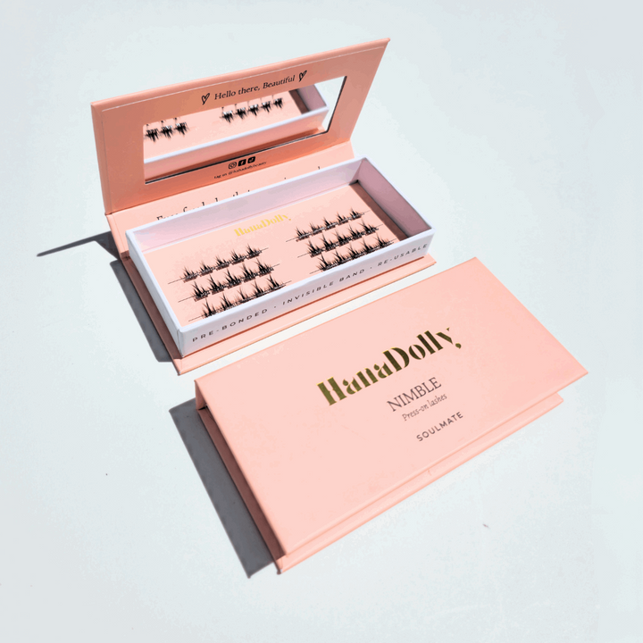 Flatlay of HanaDolly's Soulmate press-on lashes in an open pink HanaDolly box, showcasing reusable lashes with pre-bonded adhesive.