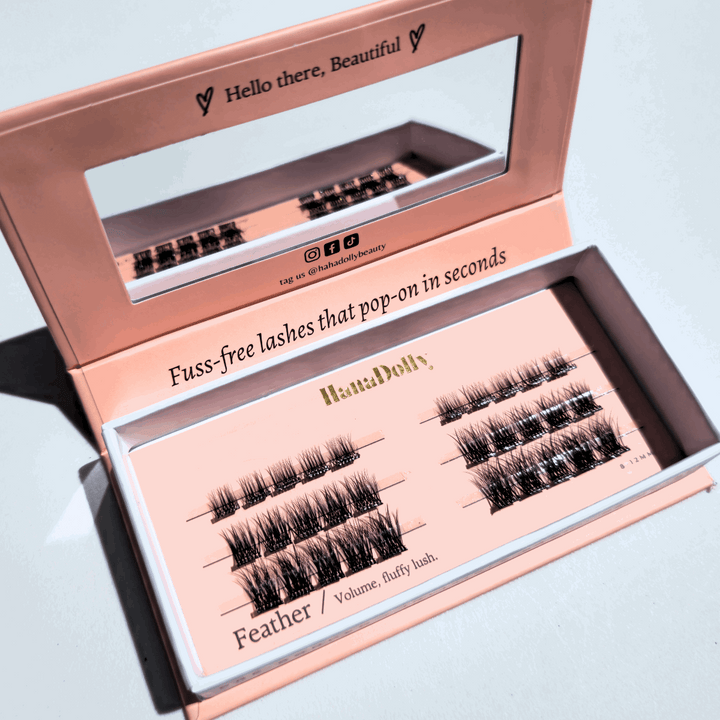 Angled flatlay of Feather press-on lashes in an open pink box, showing individual lash clusters for easy application.