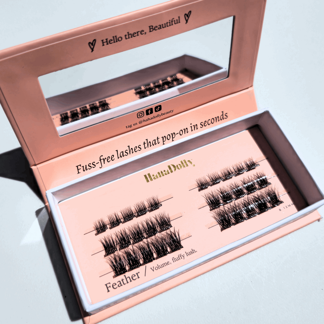 Angled flatlay of Feather press-on lashes in an open pink box, showing individual lash clusters for easy application.