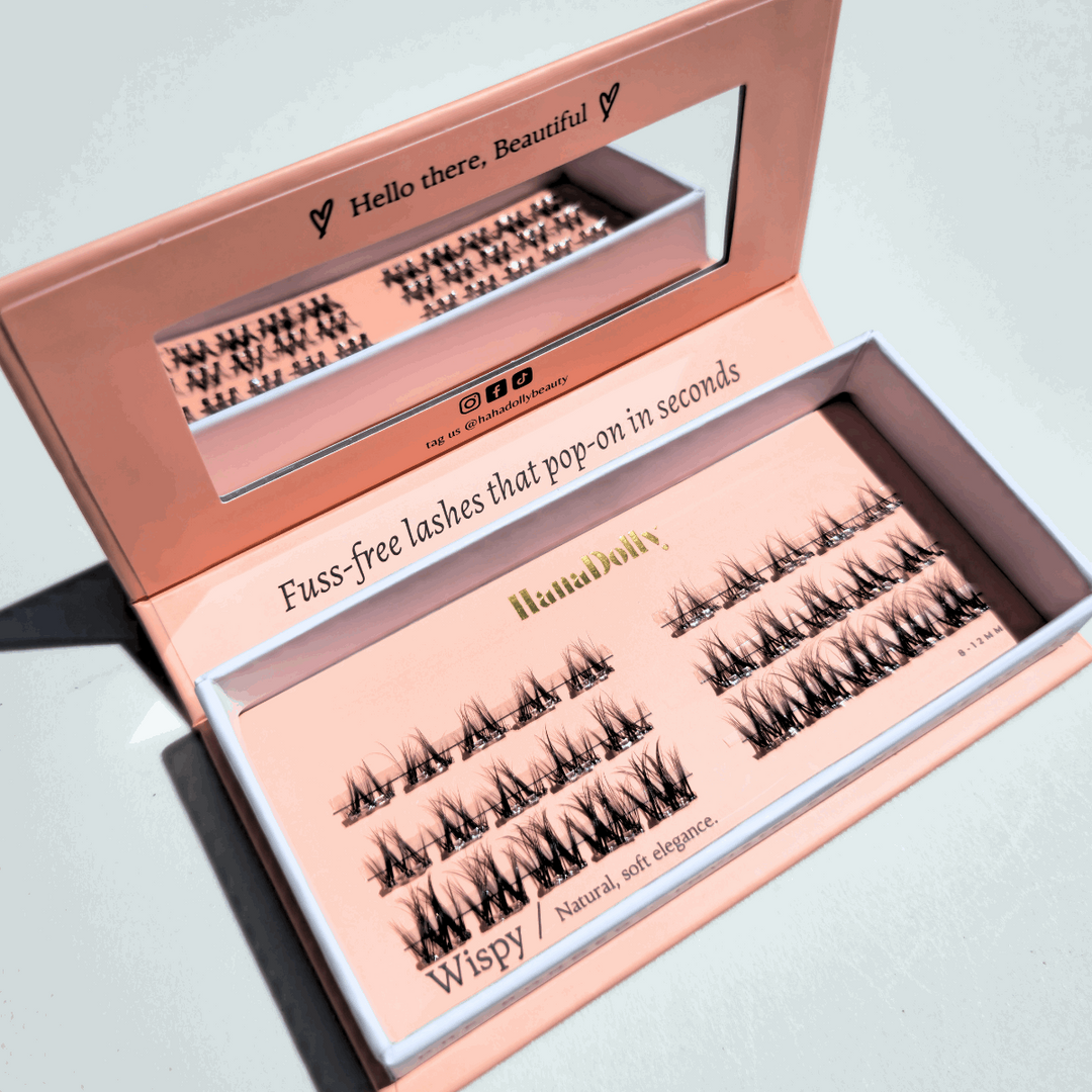 Angled flatlay of Wispy press-on lashes in an open pink box, showing individual lash clusters for easy application.