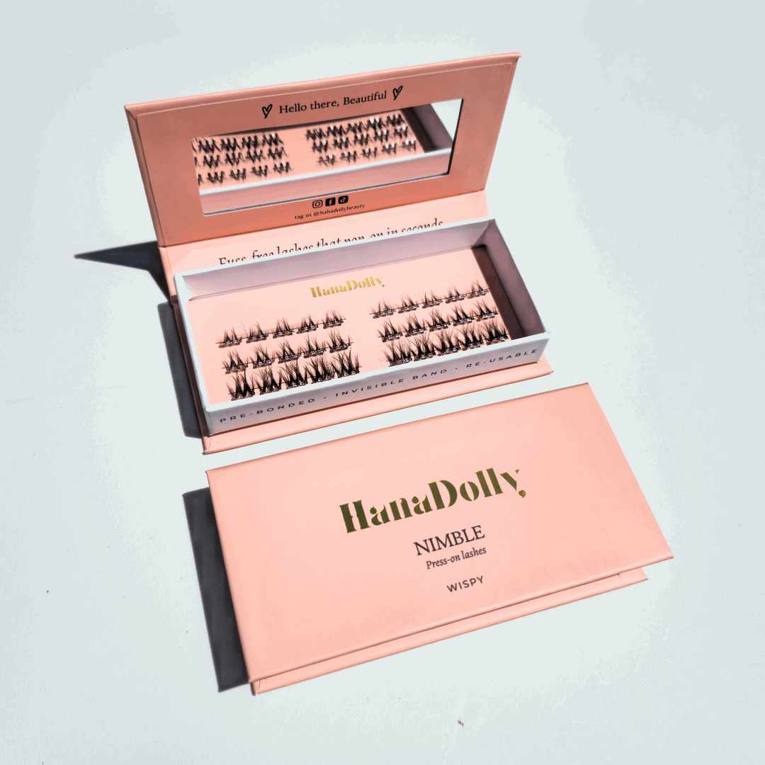 Flatlay of HanaDolly's Wispy press-on lashes in an open pink HanaDolly box, showcasing reusable lashes with pre-bonded adhesive.